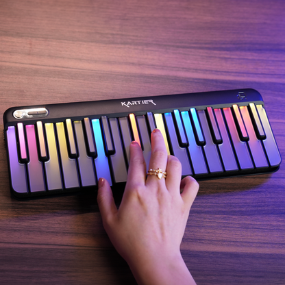 Kartier Piano Portable keyboard with colorful keys on a wooden surface, hand playing it.